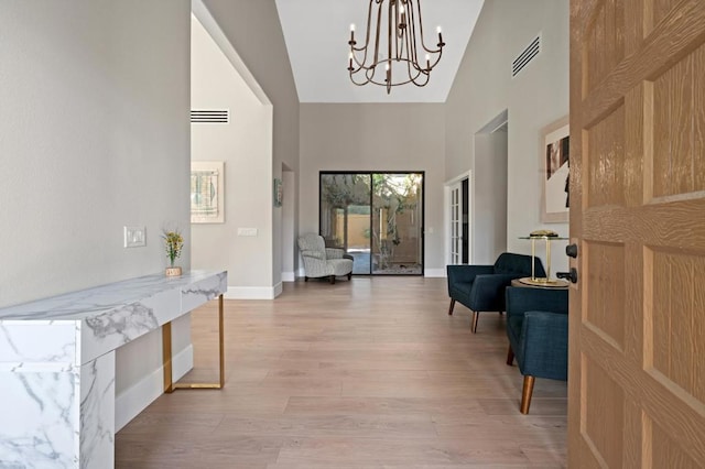 foyer entrance with a chandelier, light hardwood / wood-style flooring, and high vaulted ceiling