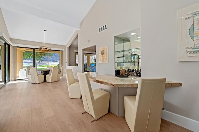 dining room with an inviting chandelier, lofted ceiling, and light wood-type flooring