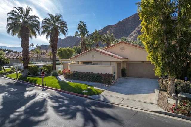 view of front of property with a mountain view, a front yard, and a garage