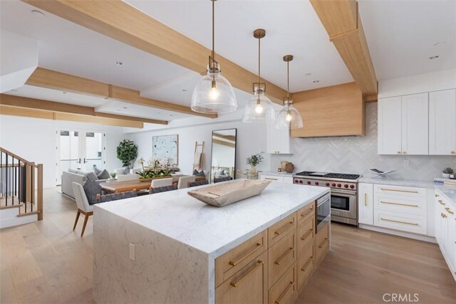 kitchen with pendant lighting, a center island, white cabinets, light wood-type flooring, and stainless steel appliances