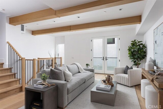 living room with beamed ceiling, light wood-type flooring, and french doors