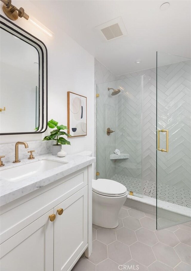 bathroom with toilet, vanity, tile patterned floors, and an enclosed shower