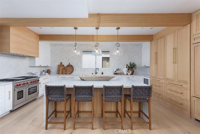 kitchen with a kitchen island, double oven range, premium range hood, and light hardwood / wood-style flooring