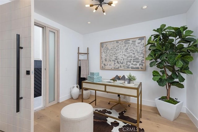 office space with an inviting chandelier and light wood-type flooring