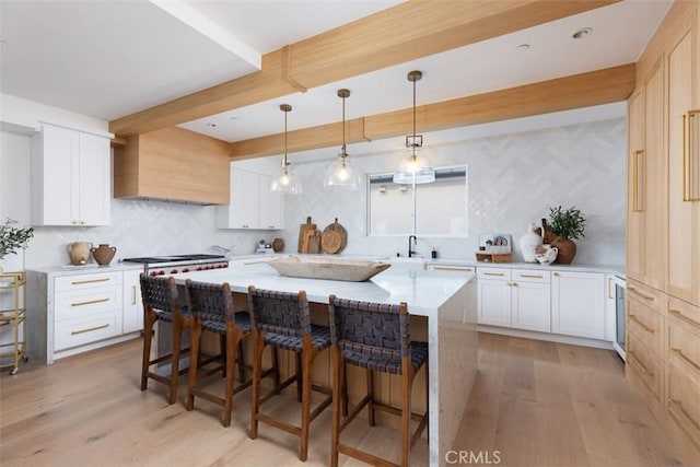 kitchen with a kitchen bar, white cabinets, light hardwood / wood-style floors, and custom range hood