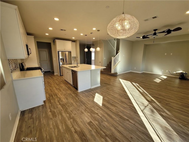 kitchen with dark hardwood / wood-style floors, decorative light fixtures, white cabinetry, a kitchen island with sink, and stainless steel appliances