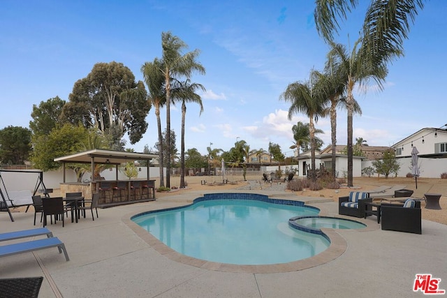 view of swimming pool featuring exterior bar, a patio, and an in ground hot tub