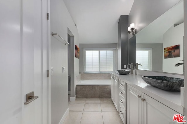 bathroom with tile patterned flooring, vanity, tiled bath, and plenty of natural light