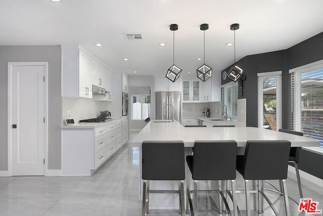 kitchen featuring white cabinets, hanging light fixtures, appliances with stainless steel finishes, and tasteful backsplash