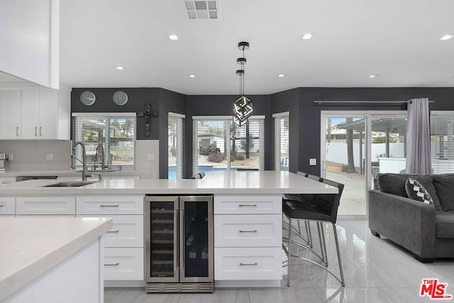 kitchen with decorative light fixtures, a healthy amount of sunlight, white cabinetry, and wine cooler