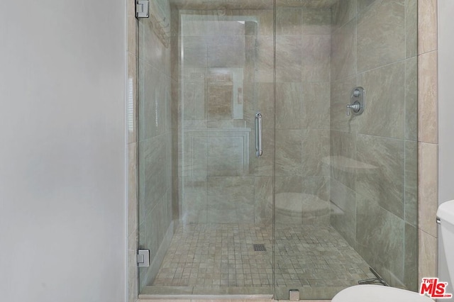 bathroom featuring toilet and a shower with shower door