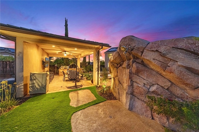 yard at dusk with a patio area, ceiling fan, and an outdoor bar