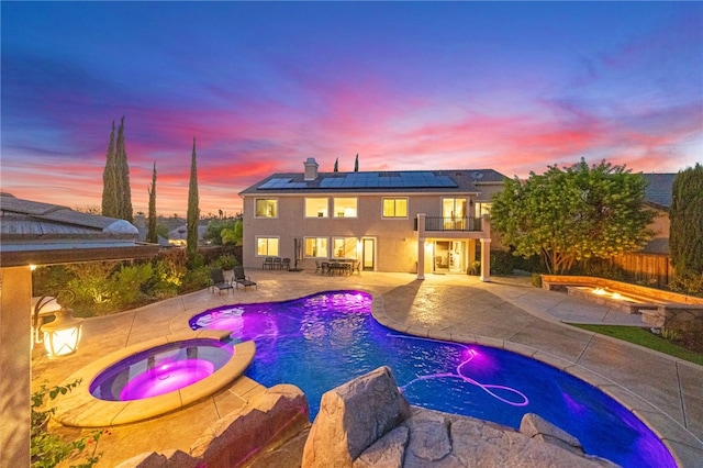 pool at dusk with an in ground hot tub and a patio