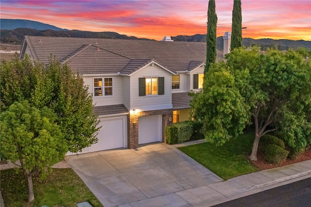 view of front facade featuring a lawn, a mountain view, and a garage