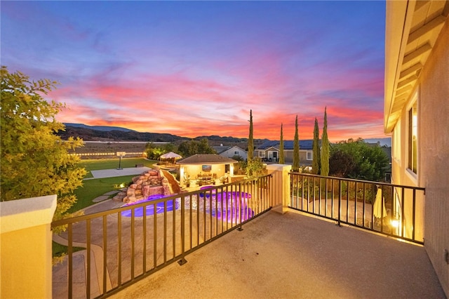 patio terrace at dusk featuring a mountain view and a balcony