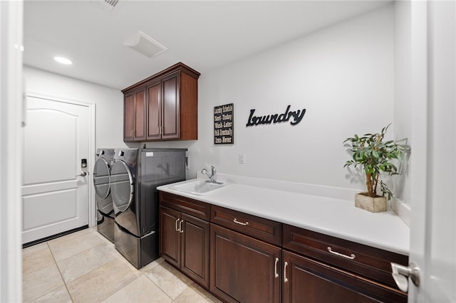 clothes washing area with cabinets, washing machine and dryer, light tile patterned flooring, and sink