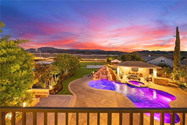 pool at dusk featuring a mountain view, an in ground hot tub, and a patio