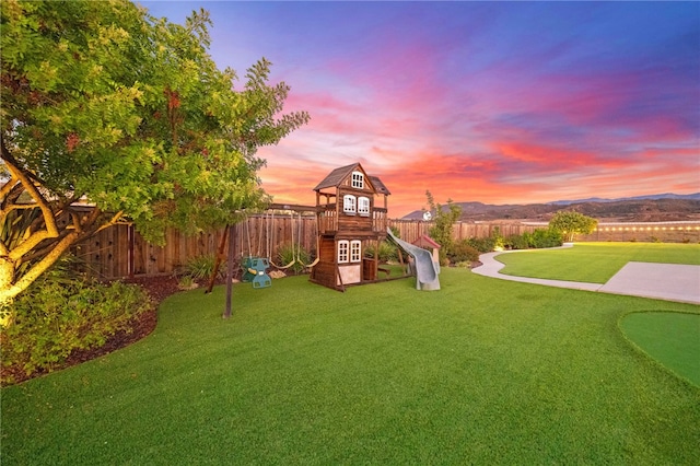 yard at dusk with a mountain view and a playground