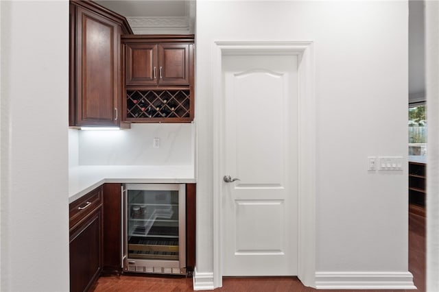 bar with dark brown cabinets, hardwood / wood-style flooring, and wine cooler