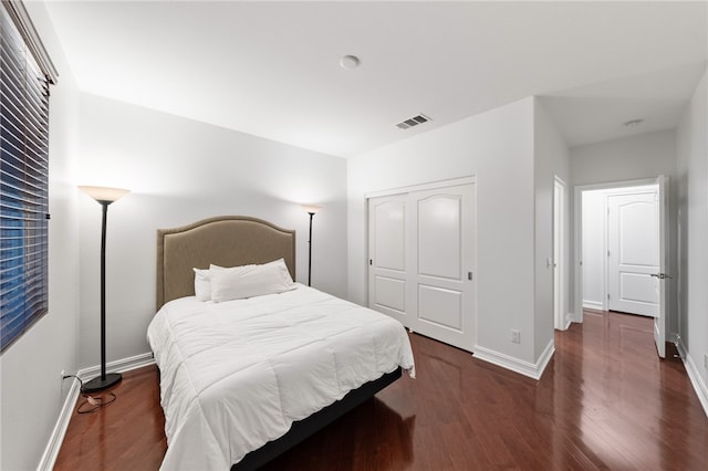 bedroom with dark wood-type flooring and a closet