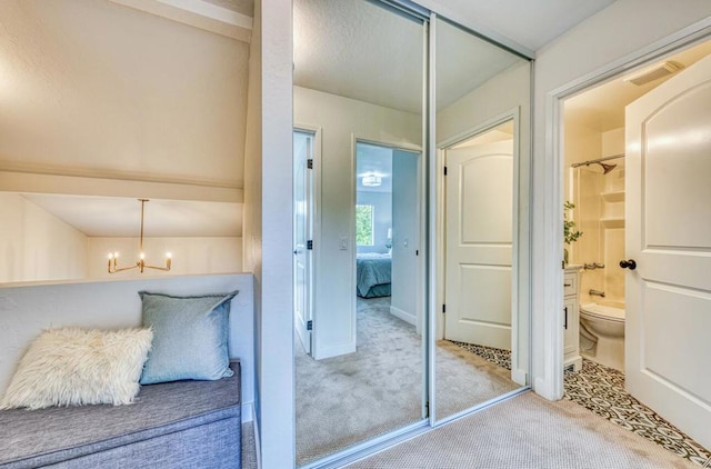 interior space with connected bathroom, a notable chandelier, light colored carpet, and a closet