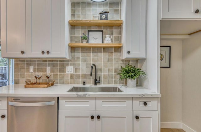 bar featuring sink, tasteful backsplash, light stone counters, dishwasher, and white cabinets