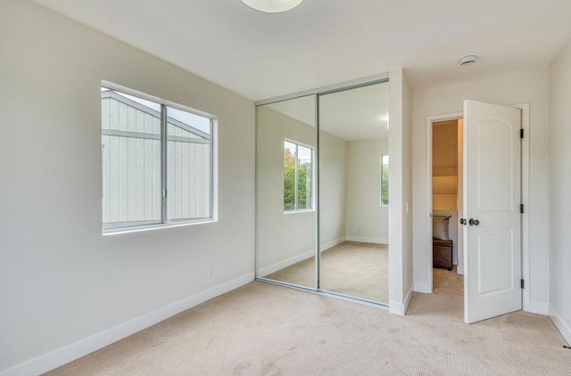 unfurnished bedroom with light carpet and a closet