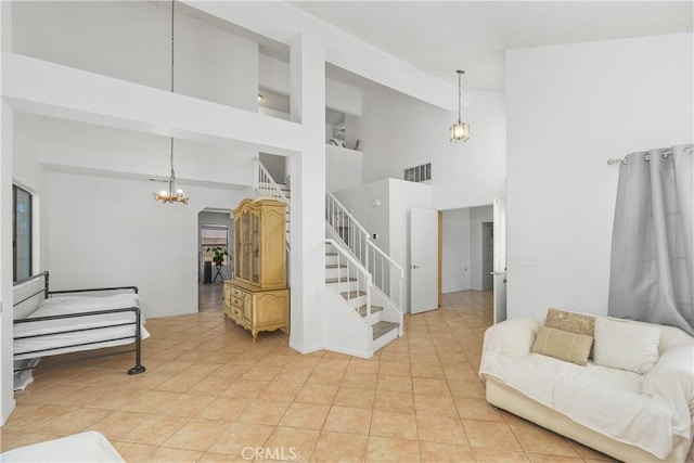 living room with a notable chandelier, a towering ceiling, and light tile patterned floors