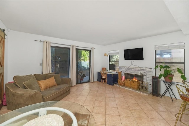 living room with light tile patterned flooring, a barn door, and a brick fireplace