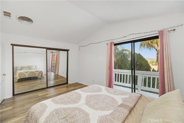 bedroom featuring access to outside, light hardwood / wood-style floors, vaulted ceiling, and a closet