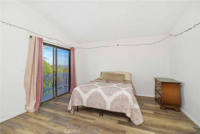 bedroom featuring access to exterior, hardwood / wood-style flooring, and vaulted ceiling