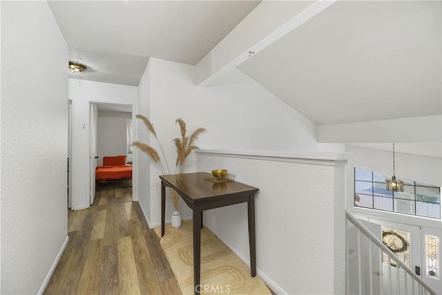 hall featuring a healthy amount of sunlight, vaulted ceiling, and wood-type flooring