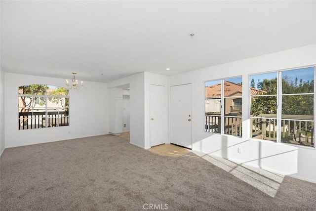 carpeted spare room with a notable chandelier