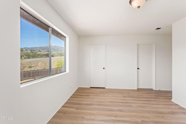 unfurnished bedroom with light wood-type flooring and a mountain view