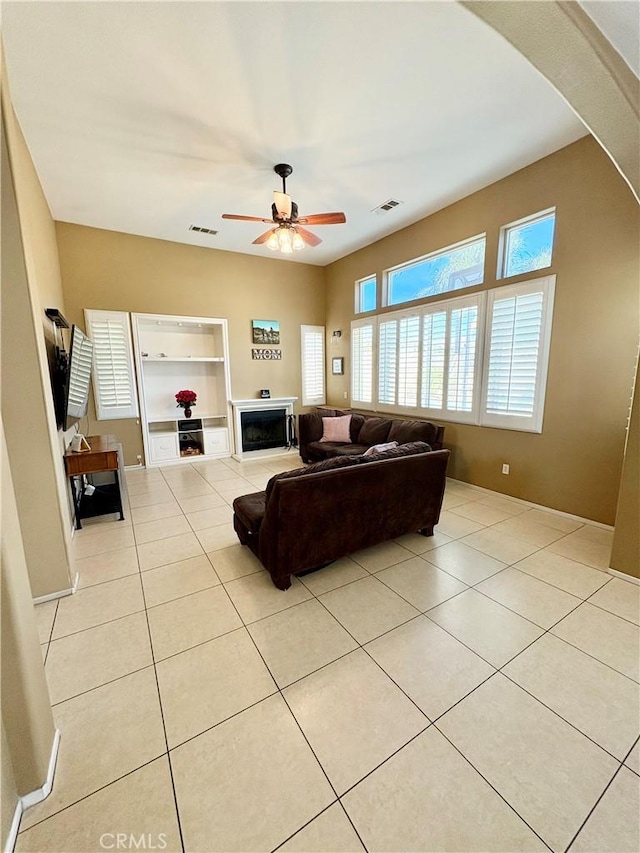 living room with visible vents, arched walkways, light tile patterned flooring, and a ceiling fan