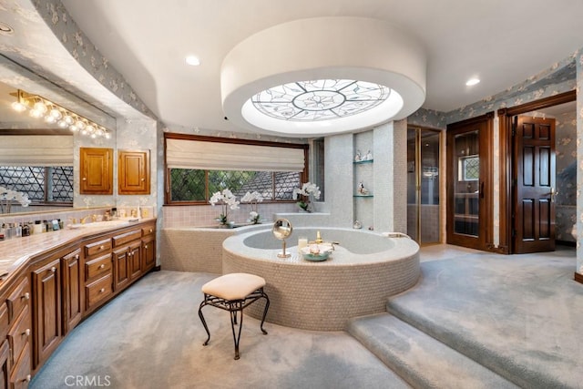 bathroom featuring a relaxing tiled tub and vanity