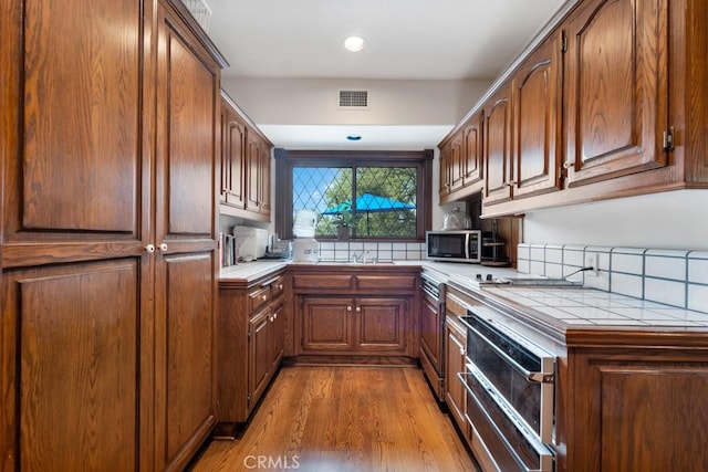 kitchen featuring sink, tile counters, and light wood-type flooring