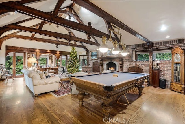 game room featuring lofted ceiling with beams, light wood-type flooring, pool table, a large fireplace, and brick wall