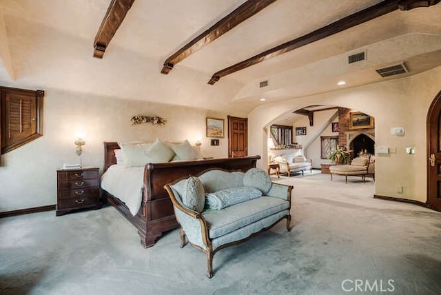 bedroom featuring beam ceiling, light carpet, and a large fireplace