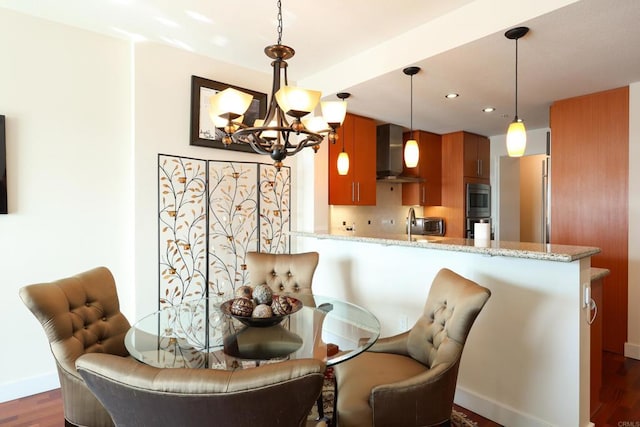 dining space with sink, dark hardwood / wood-style floors, and an inviting chandelier