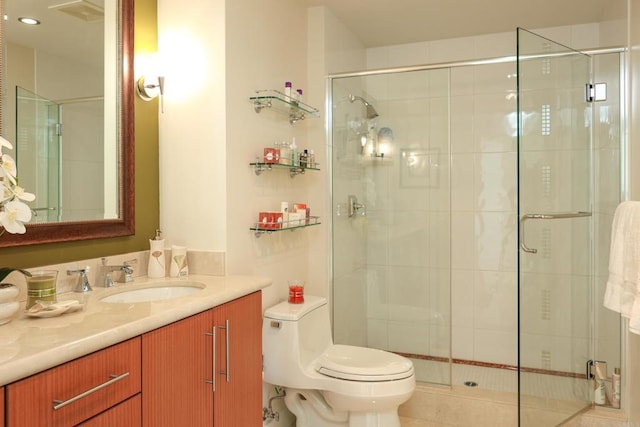 bathroom featuring a shower with shower door, toilet, and vanity