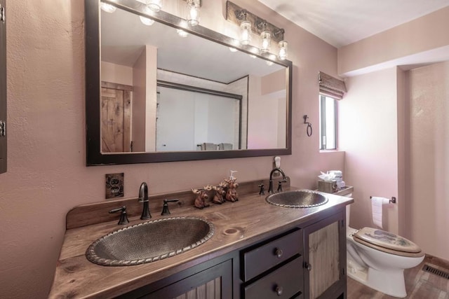 bathroom with toilet, vanity, and hardwood / wood-style flooring