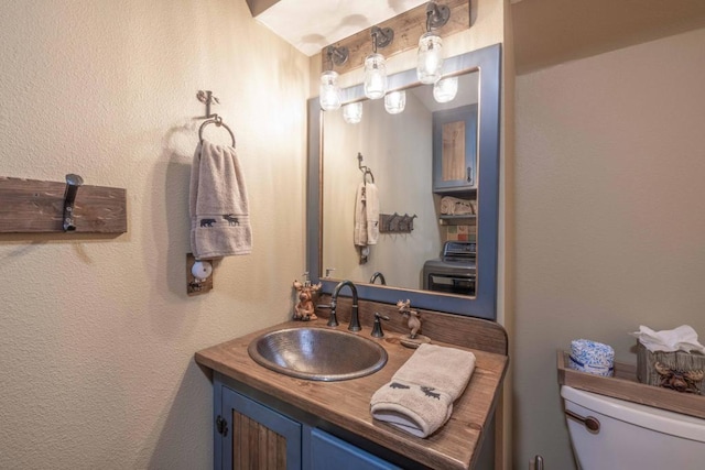 bathroom with toilet, vanity, and washer / dryer