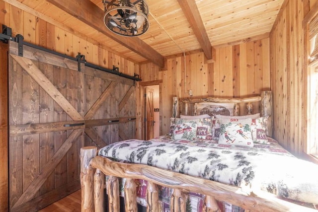 unfurnished bedroom featuring wood ceiling, a barn door, hardwood / wood-style floors, wood walls, and beam ceiling