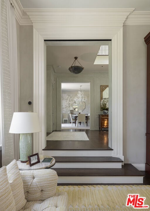 hall with an inviting chandelier and ornamental molding