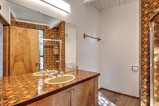 bathroom featuring toilet, vanity, beamed ceiling, and hardwood / wood-style flooring