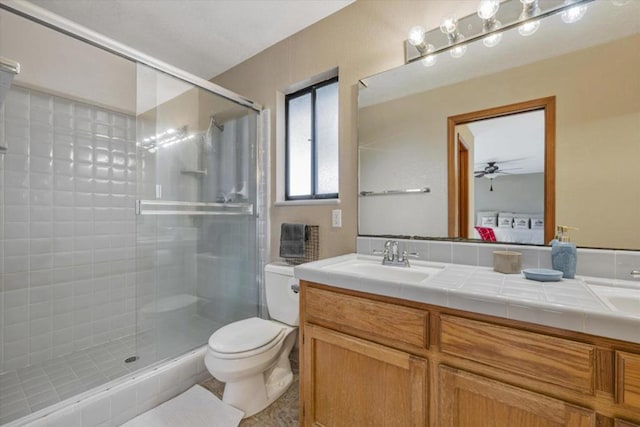 bathroom with ceiling fan, vanity, toilet, and walk in shower