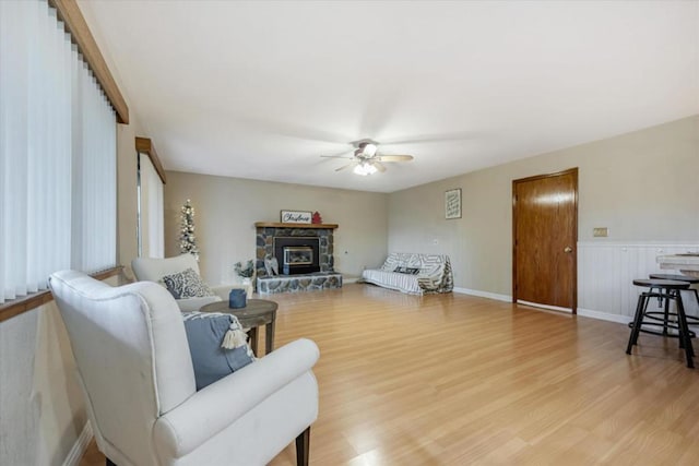 living room with ceiling fan, a fireplace, and light hardwood / wood-style flooring