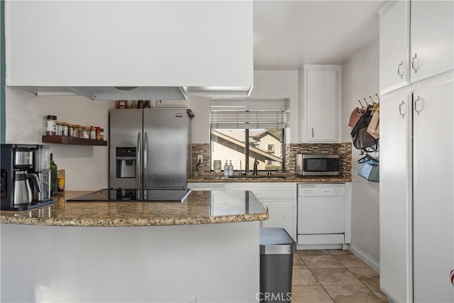 kitchen with stainless steel appliances, white cabinetry, dark stone counters, and sink