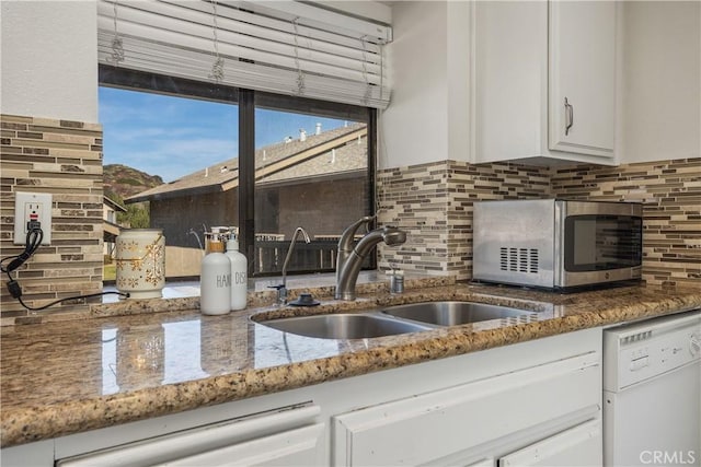 kitchen with white dishwasher, white cabinets, sink, and tasteful backsplash